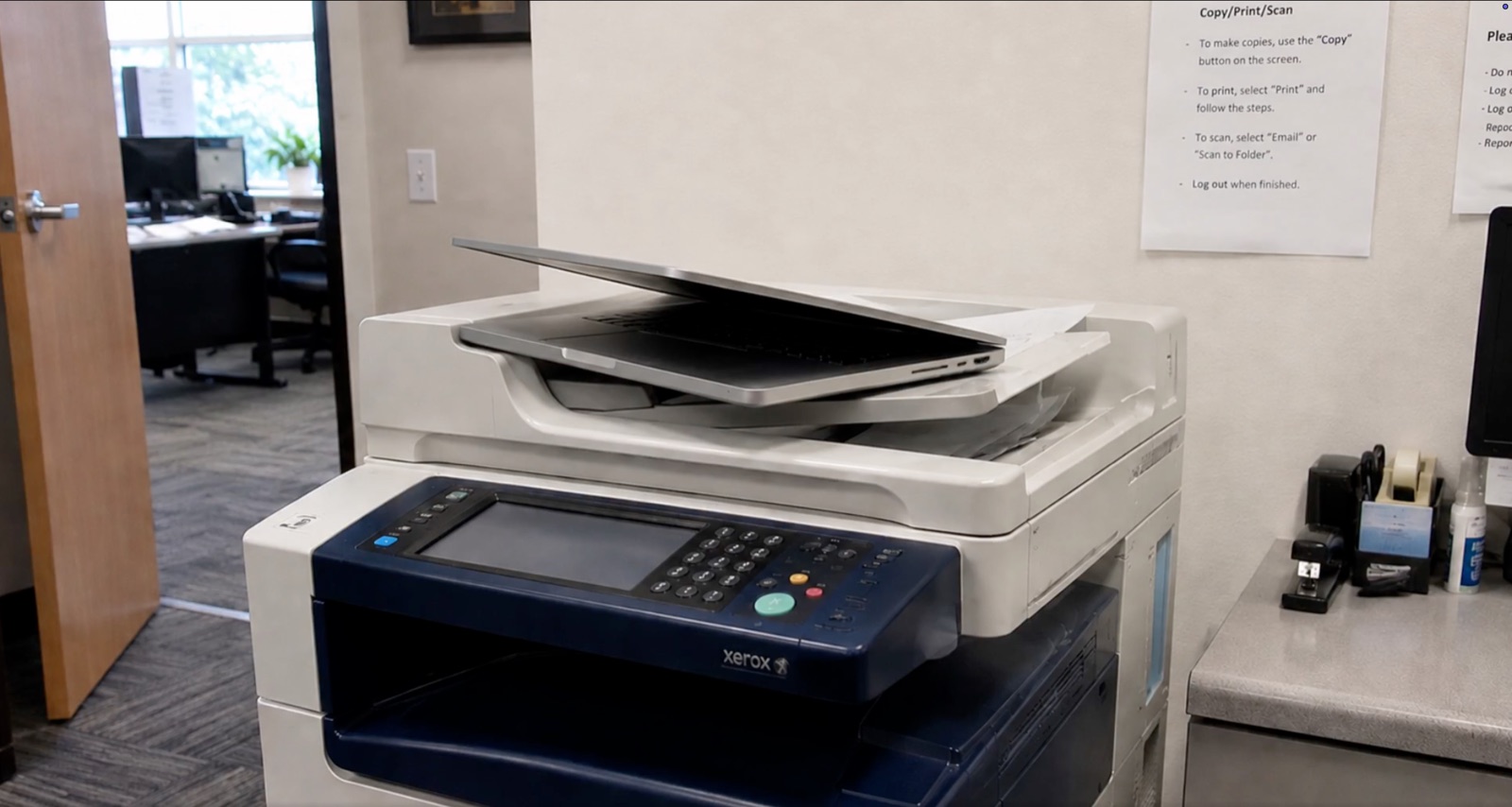a macbook propped open on a xerox photocopier so the lid doesn't close
